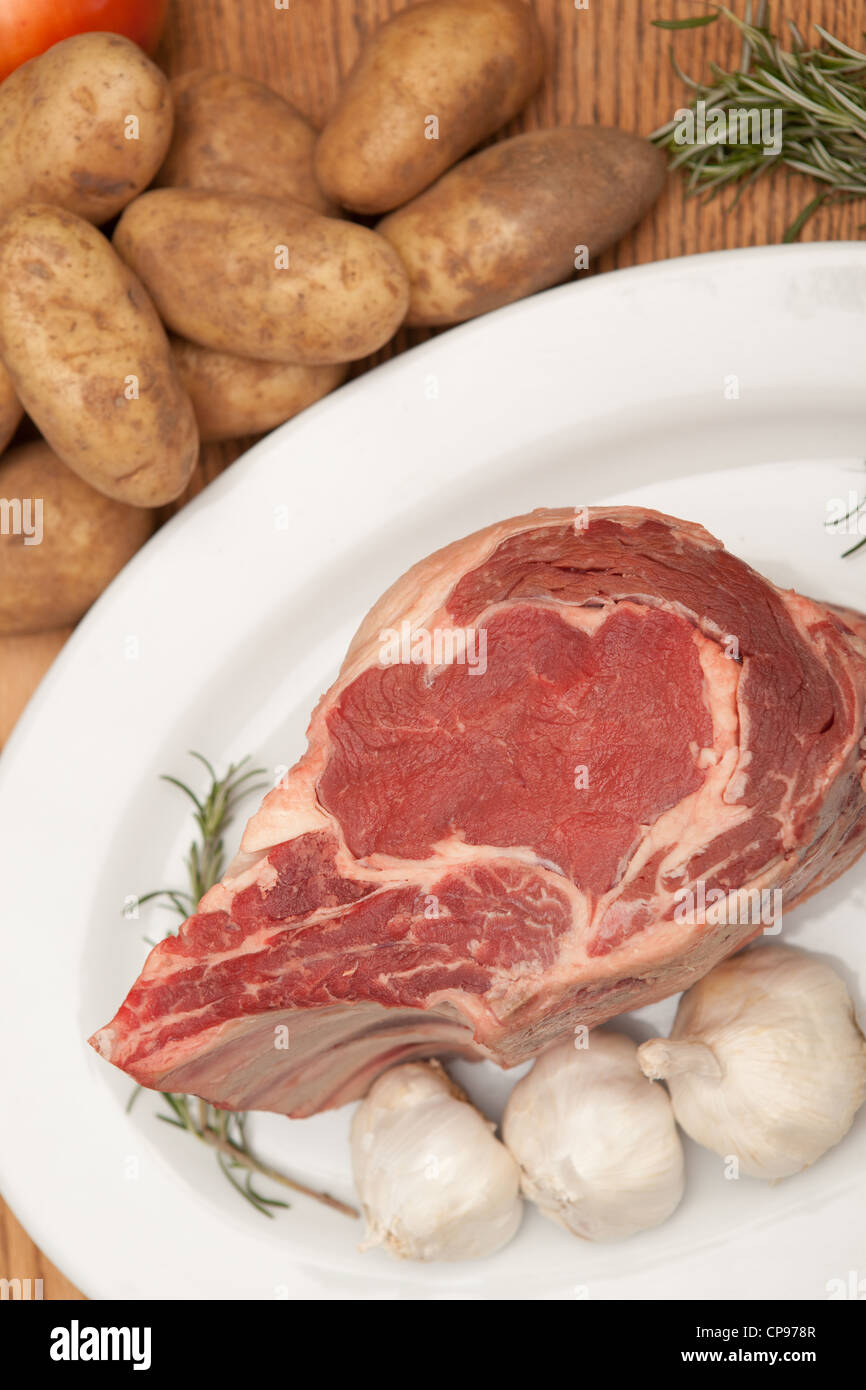 https://c8.alamy.com/comp/CP978R/vertical-view-of-a-large-uncooked-prime-rib-roast-along-with-garnishes-CP978R.jpg