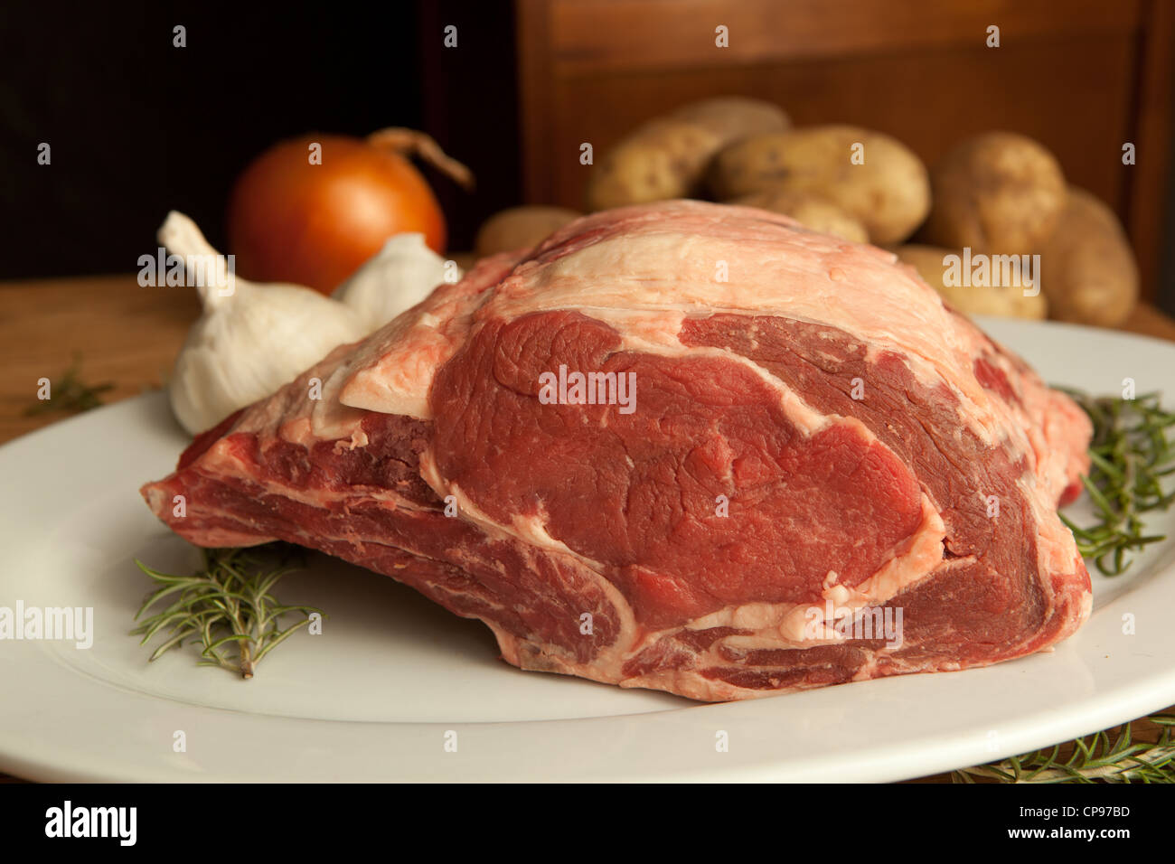 View of large bone in prime rib beef roast garnished with herbs and vegetables. Stock Photo