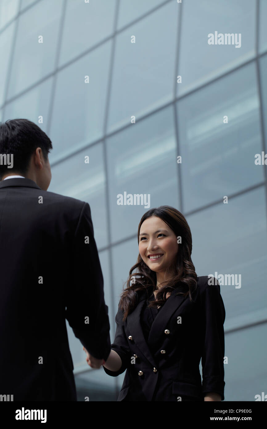 Man and woman shaking hands in front of building Stock Photo - Alamy