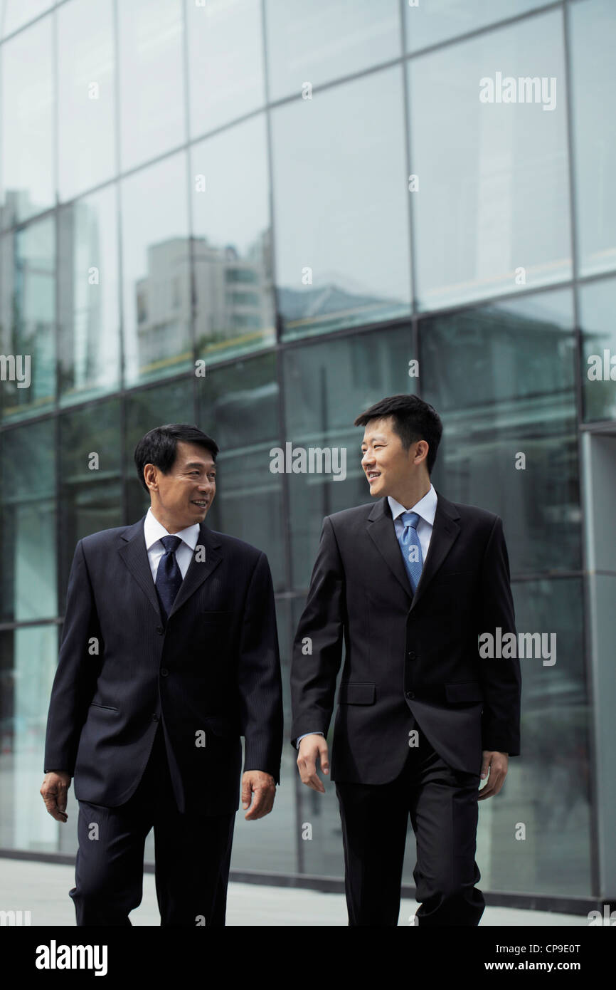 Businessmen walking together in front of a building Stock Photo - Alamy