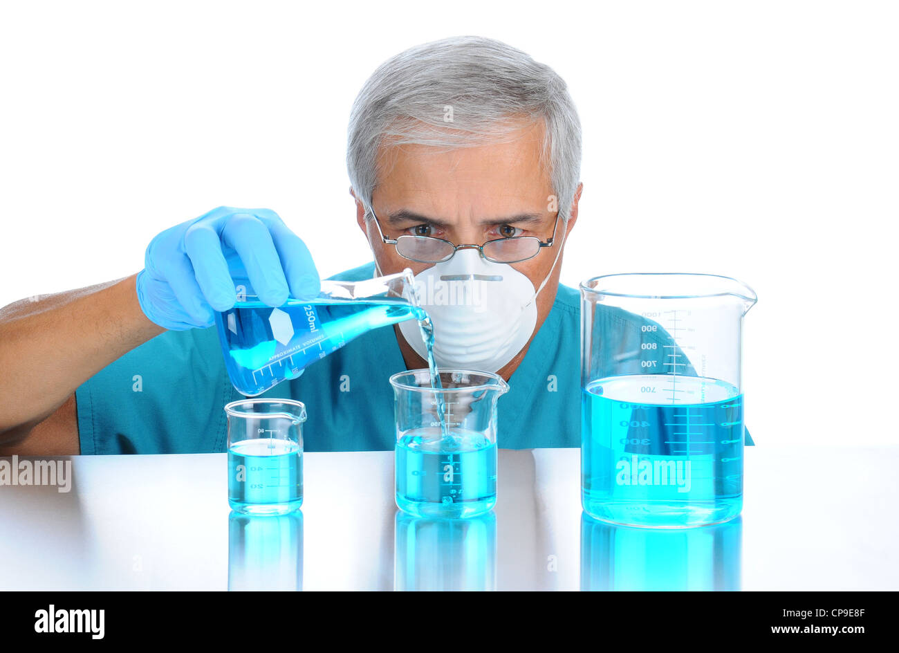 Scientist pouring measuring liquids in assorted beakers. Horizontal format over white background. Stock Photo