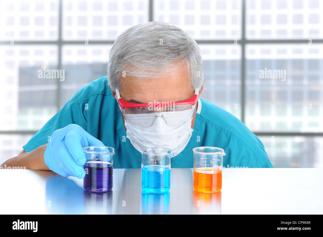 Scientist in modern laboratory with protective mask and goggles examining laboratory beakers filled with different chemicals. Stock Photo