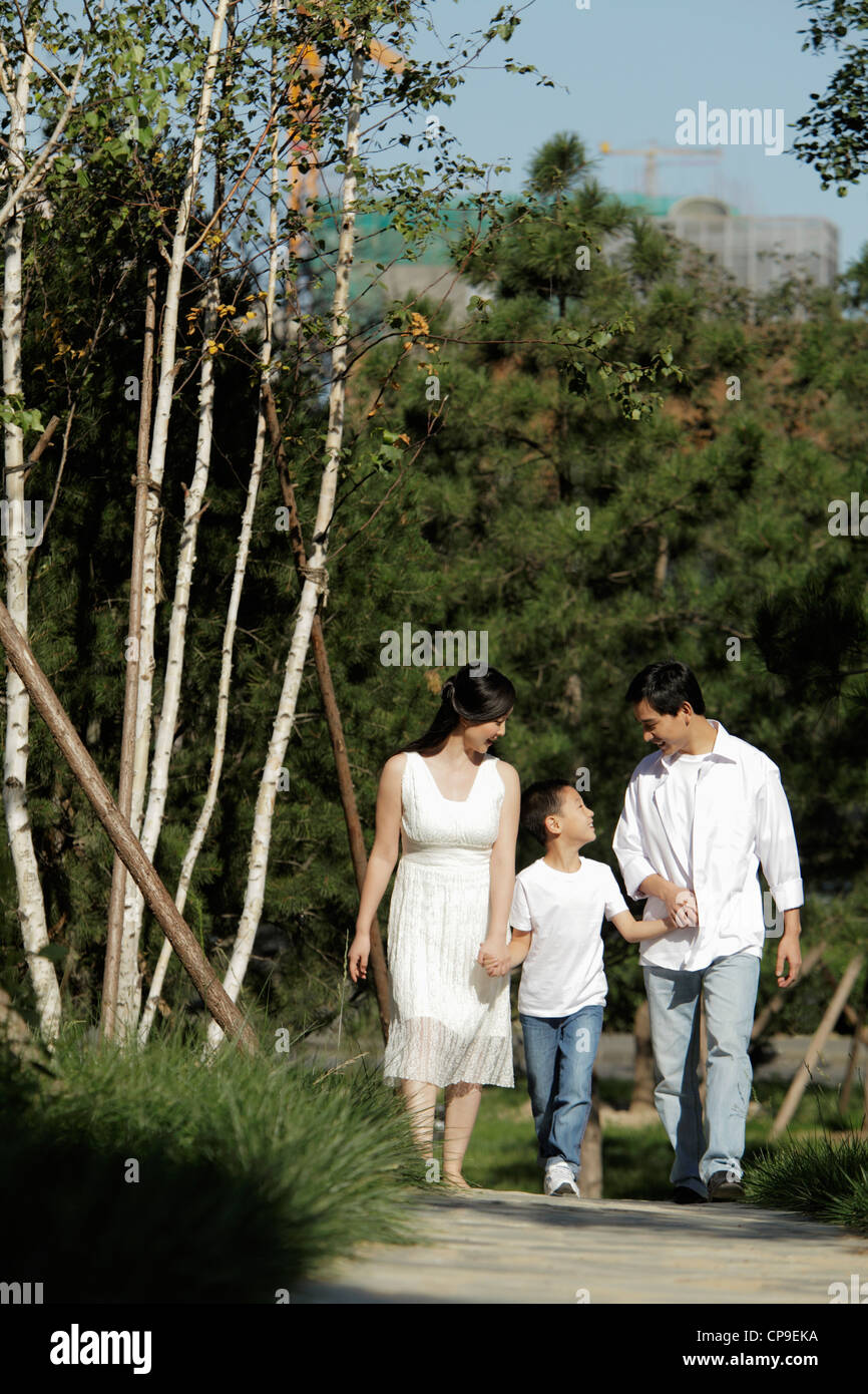 Young family holding hands walking down path Stock Photo - Alamy