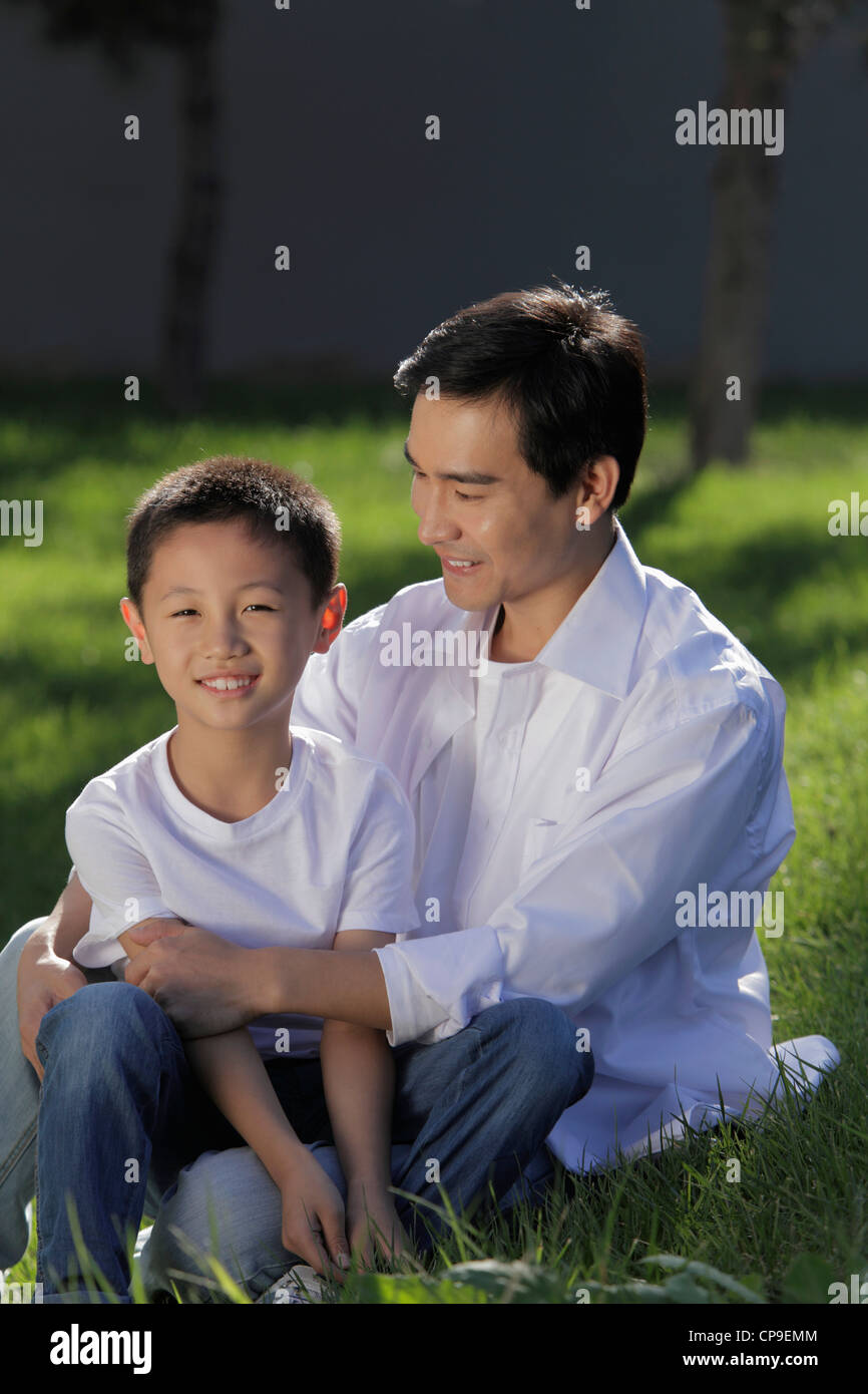 Father and son sitting on grass together Stock Photo - Alamy