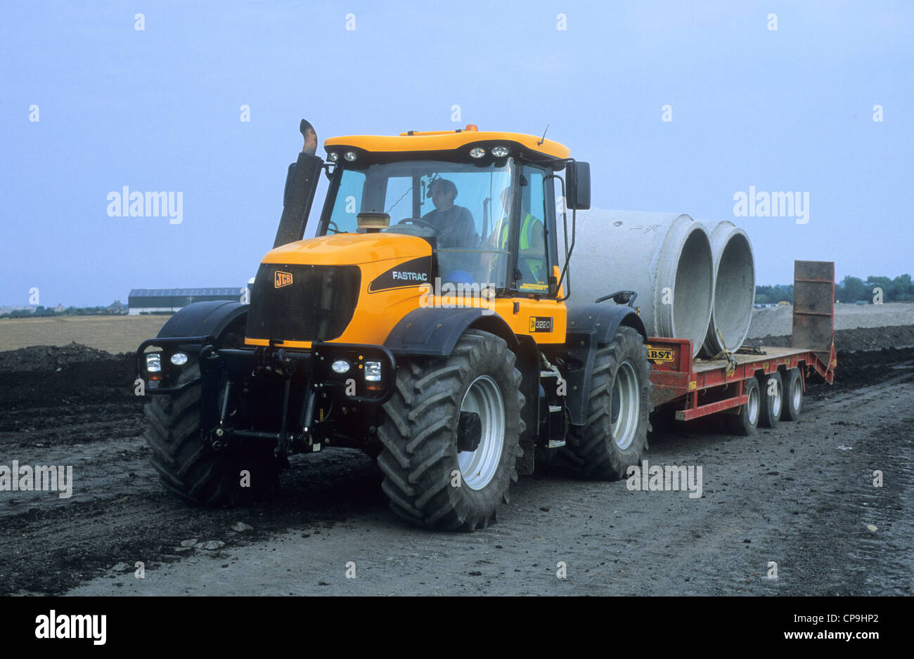 A 'JCB Fastrac 3220' Construction Vehicle towing concrete piping tubes over a land re-development site. Stock Photo