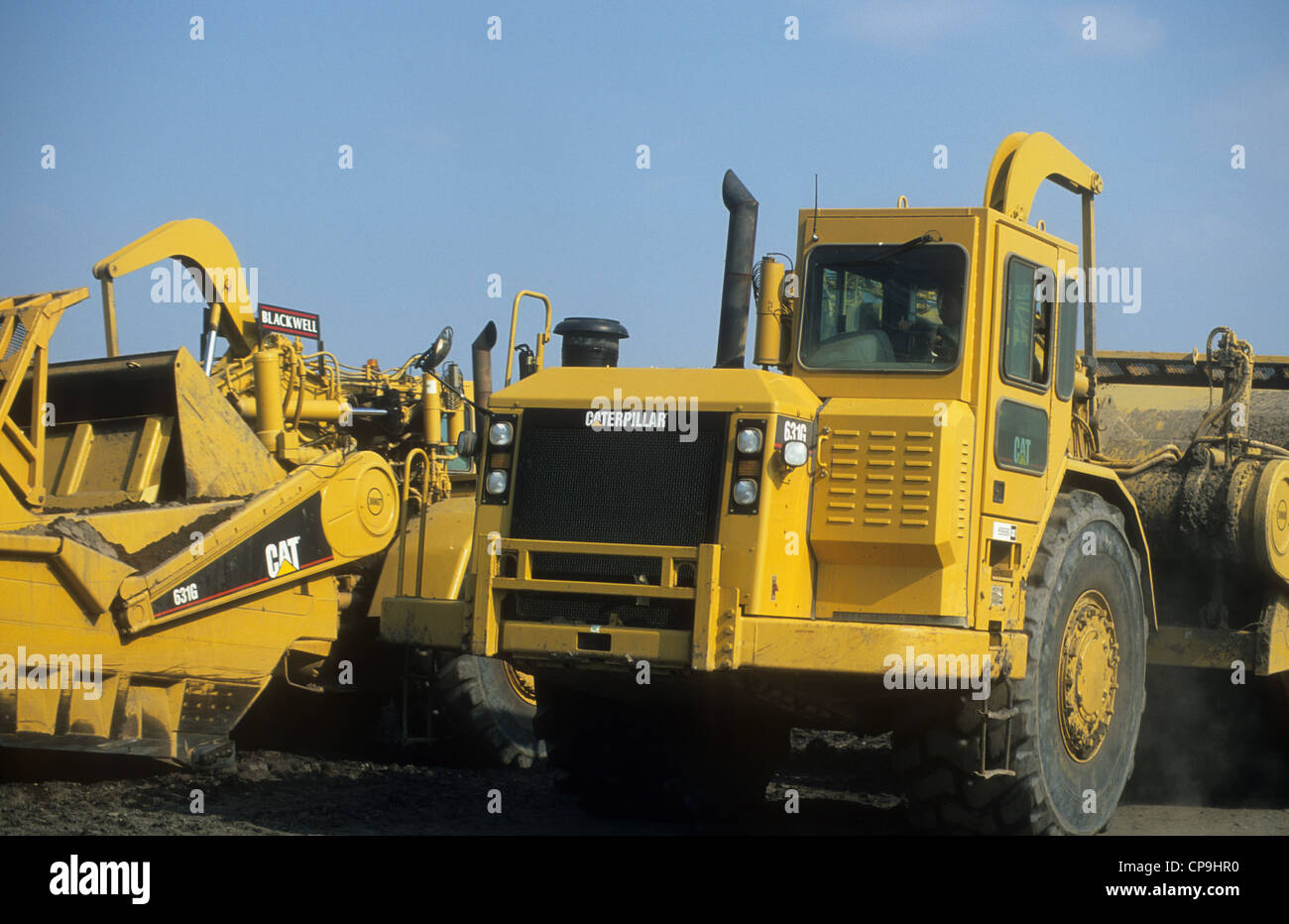 Two Caterpillars-631G articulated landscraper vehicles transversing upon a land redevelopment site. Stock Photo