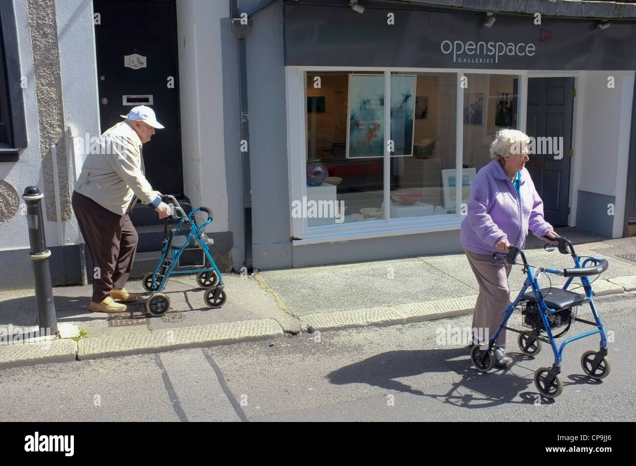 Two senior citizens with walking frames in Falmouth, Cornwall crossing the road Stock Photo