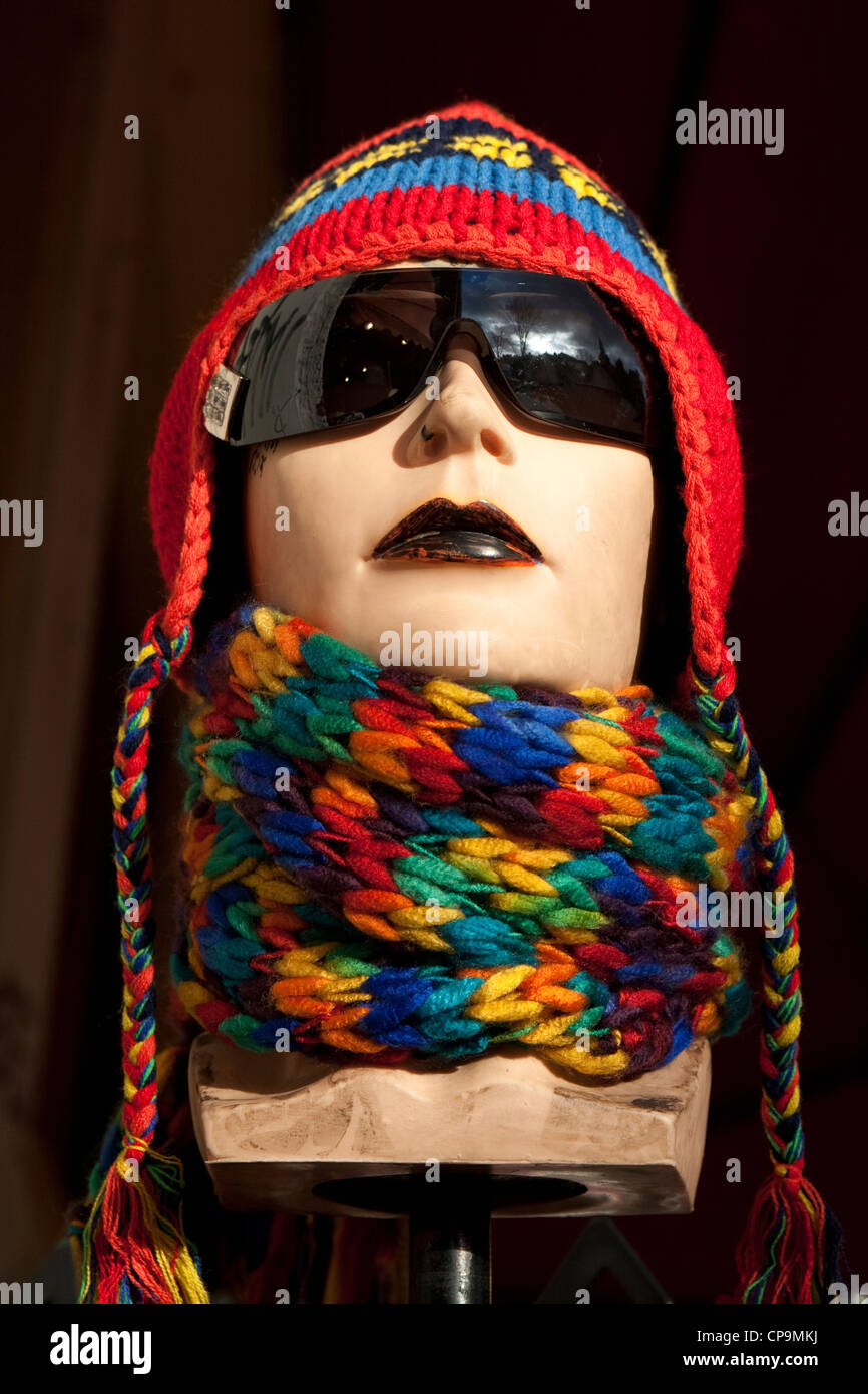 A mannequin head dressed in colourful hat and scarf in a shop window