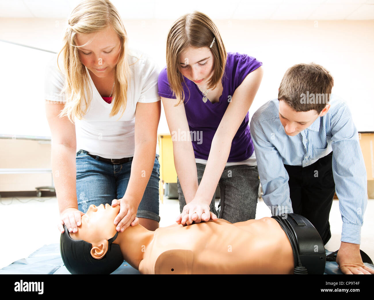 Students practicing CPR life saving techniques on a mannequin. Stock Photo