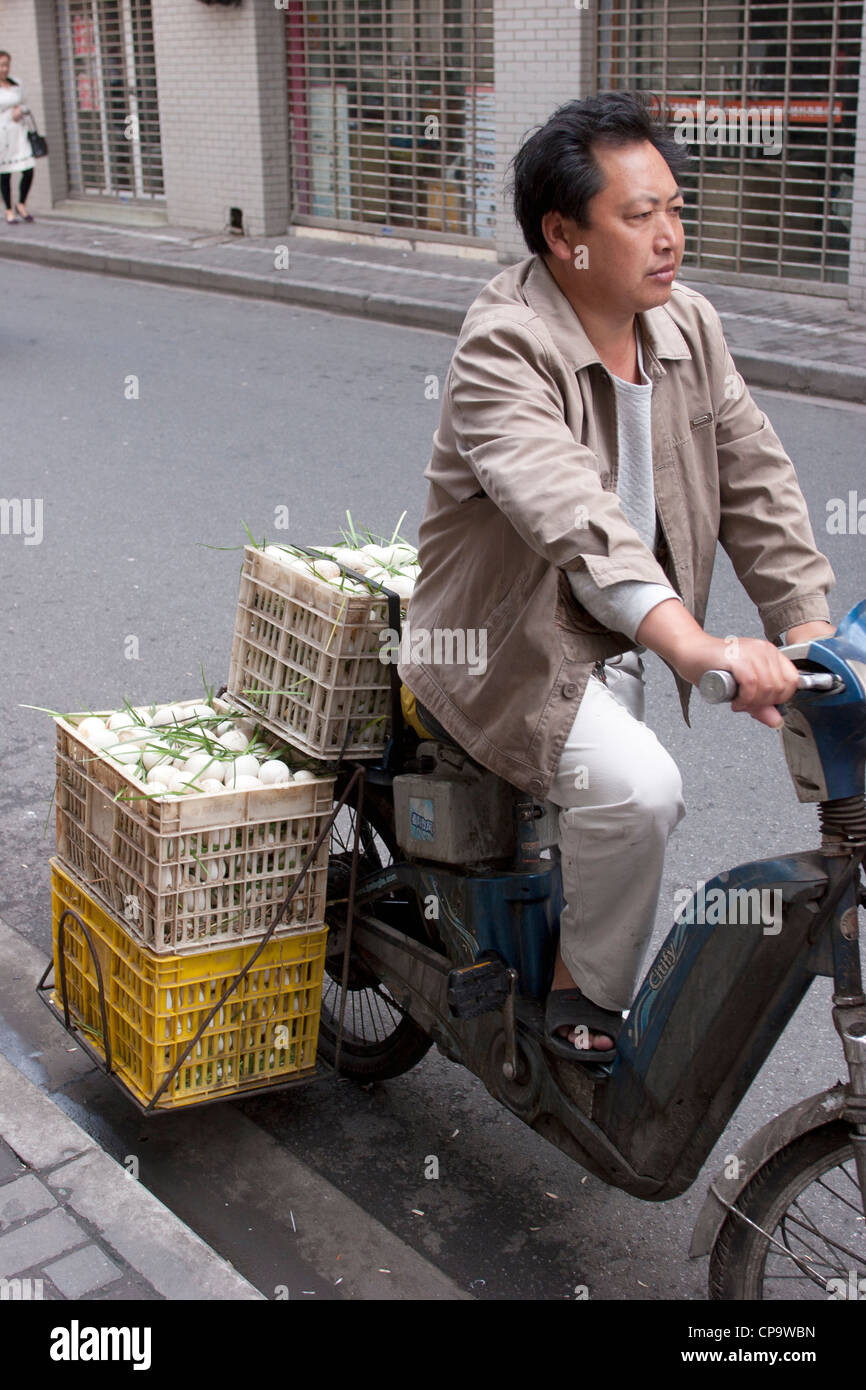 A man on a moped with a fragile cargo of white eggs, Shanghai, China. Stock Photo