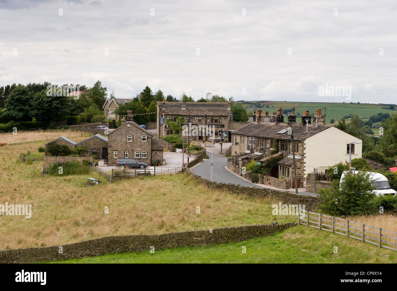 High view over B6141 road, running through village of Oxenhope (traditional stone roadside cottages & Lamb Inn pub) - West Yorkshire, England, UK. Stock Photo