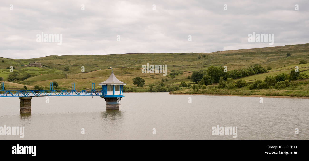 Calm water of Leeming Reservoir (footbridge, ornate valve tower) set in exposed moorland of Pennine uplands - Nr Oxenhope, West Yorkshire, England, UK Stock Photo