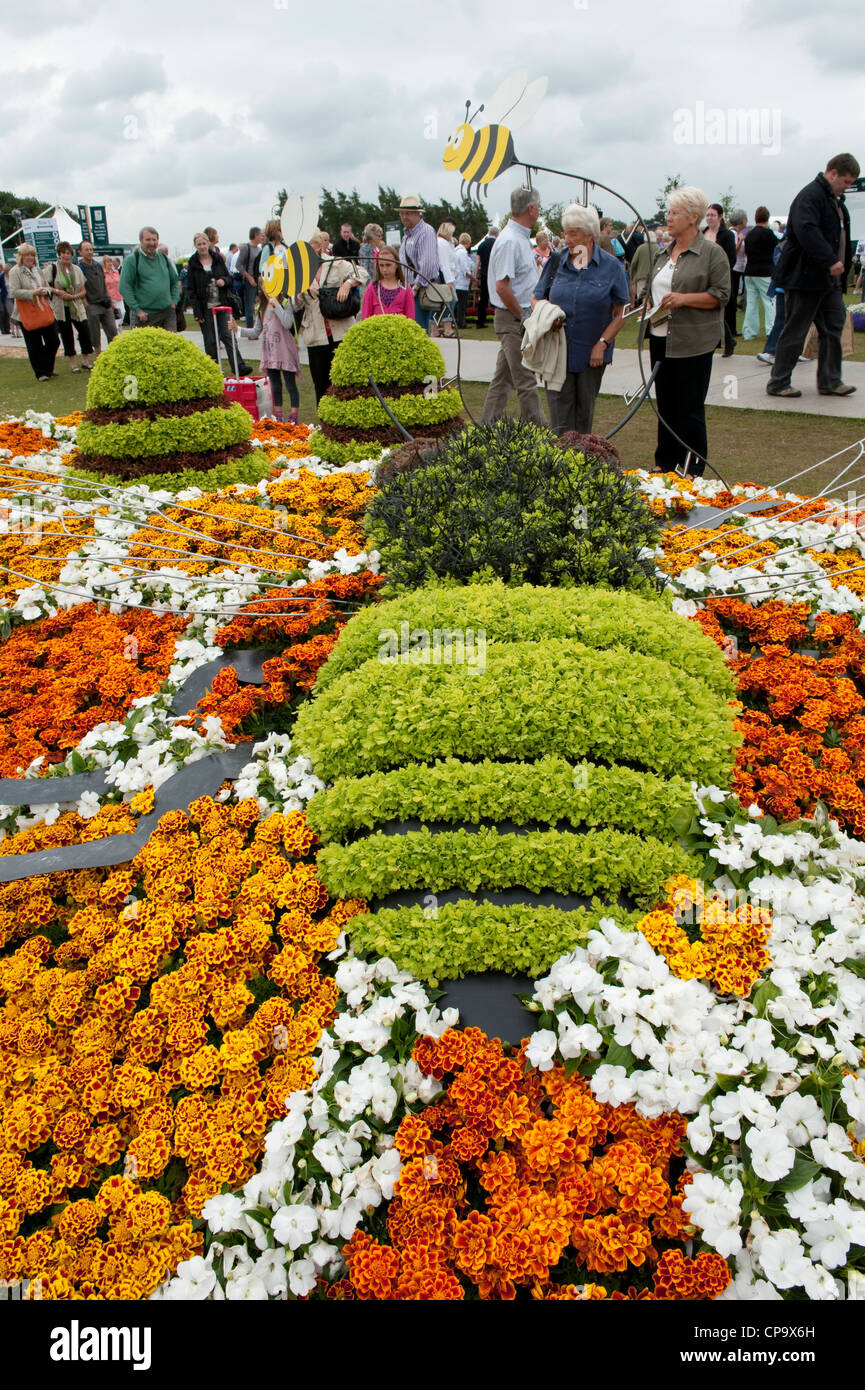 People view bright colourful flowers of beautiful prize-winning eco-friendly show garden, 'Save Our Swarm' - RHS Tatton Park Flower Show, England, UK. Stock Photo