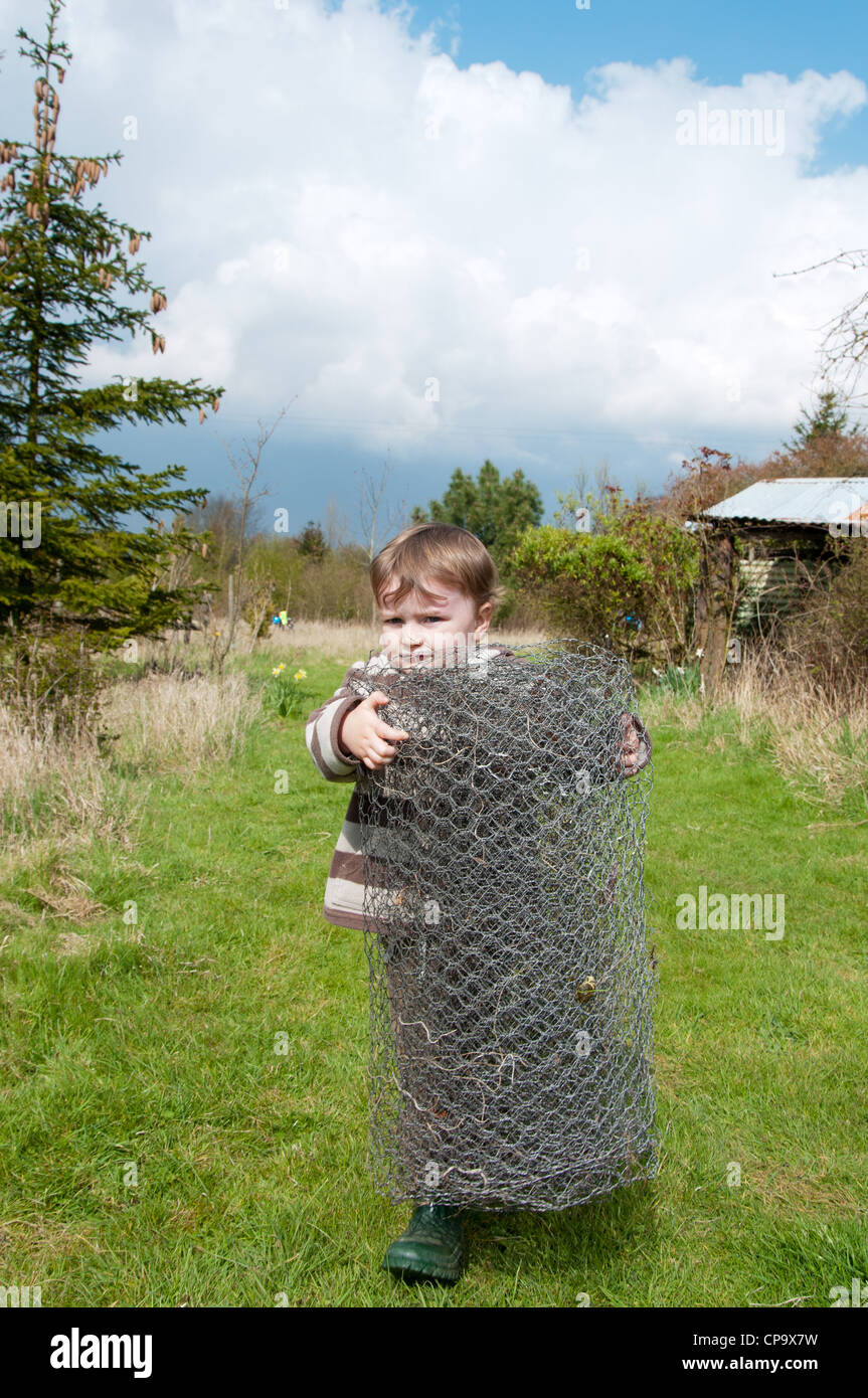 Small boy carrying roll of chicken wire Stock Photo