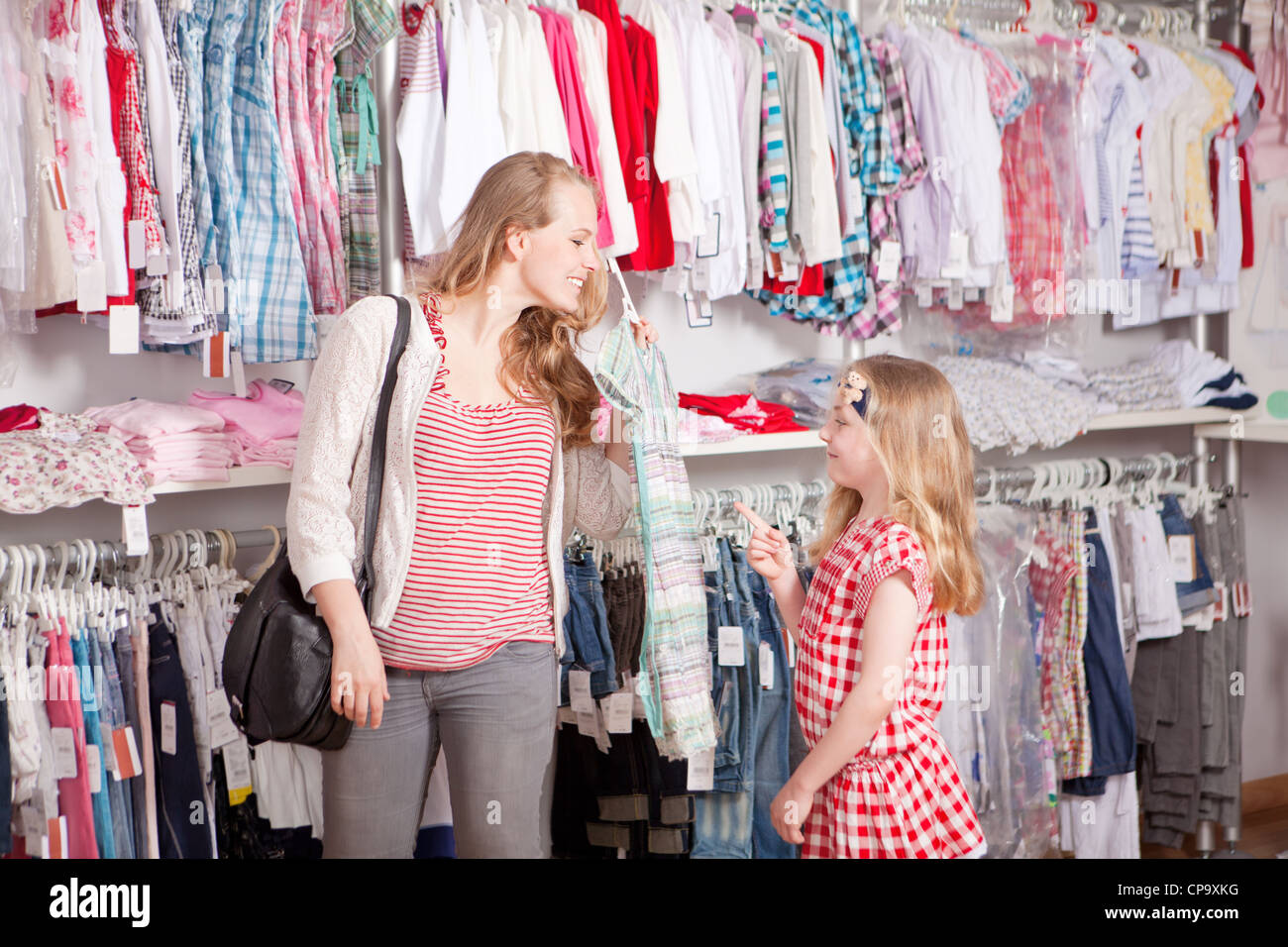 mother and child shopping choosing dress in clothes shop Stock Photo