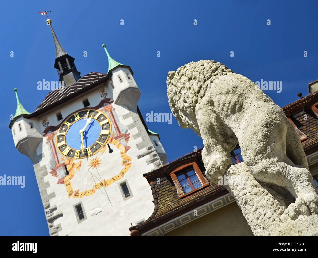Lion statue looking at Hanseatic Clock tower at the entrance to Baden in the Swiss canton of Aargau. Stock Photo