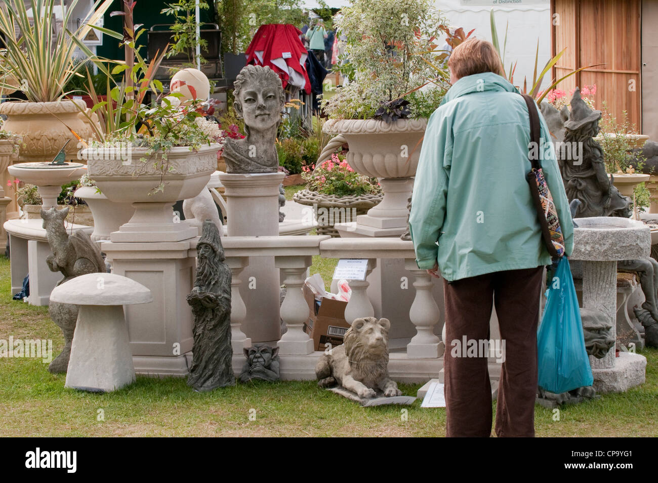 Woman stops to look at trade stand display of garden features (ornamental planters, bird baths, sculptures) - RHS Flower Show Tatton Park, England, UK Stock Photo