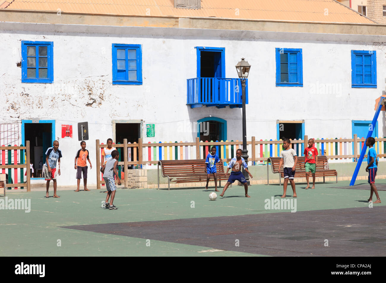 Local boys playing football barefoot in the children's playground in main square. Largo Santa Isobel, Sal Rei, Boa Vista, Cape Verde Islands Stock Photo