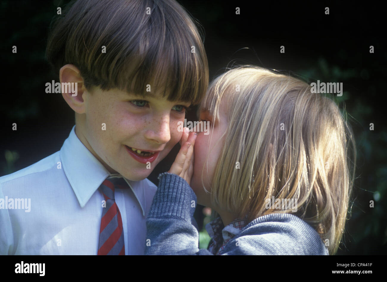 little girl whispering into boy's ear Stock Photo Alamy