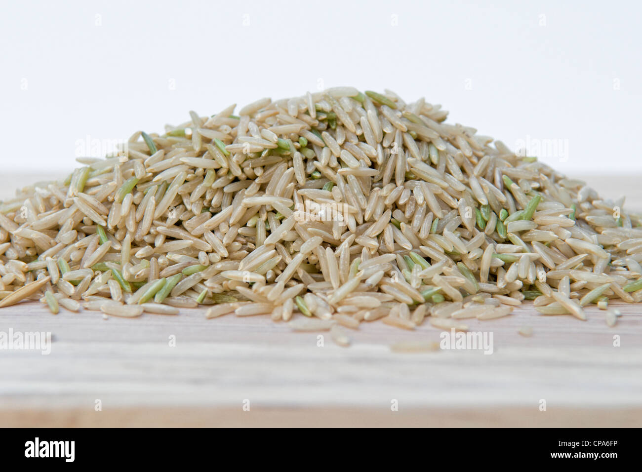 Uncooked brown basmati rice on chopping board against a white ...