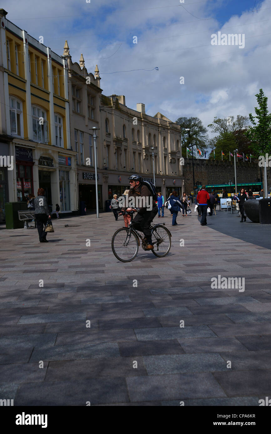 Man peddling his bike in the street in Cardiff city center Stock Photo