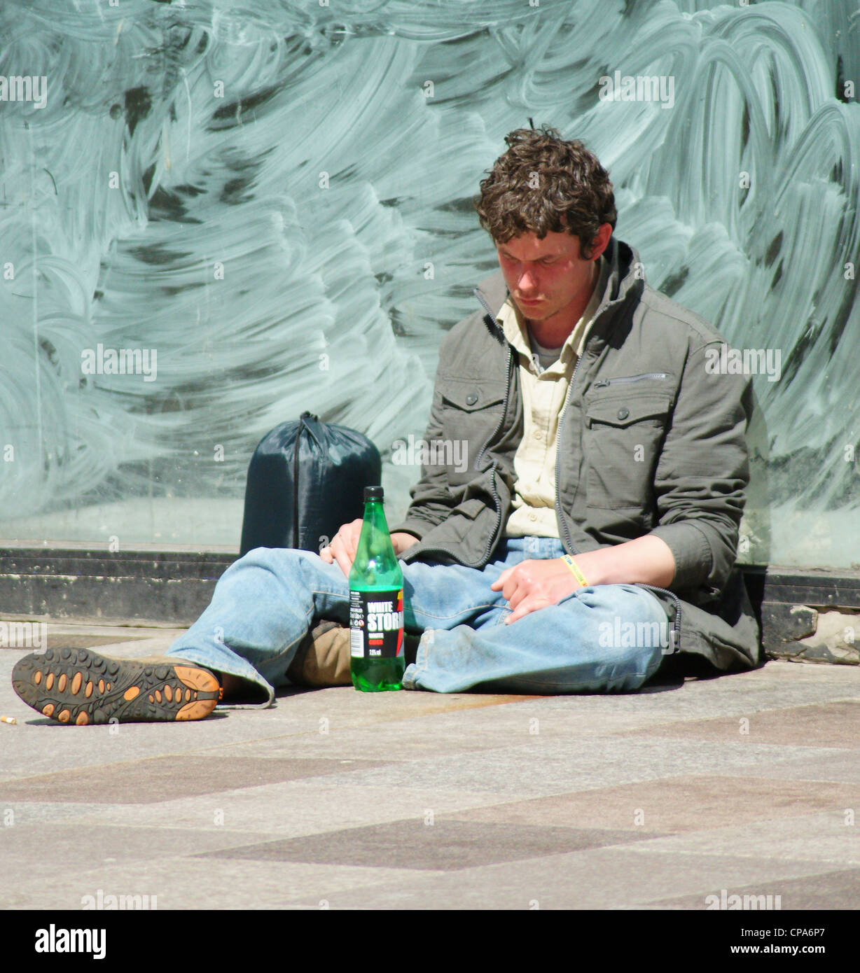 young down and out drunk sleeping on the street in Cardiff city center Stock Photo