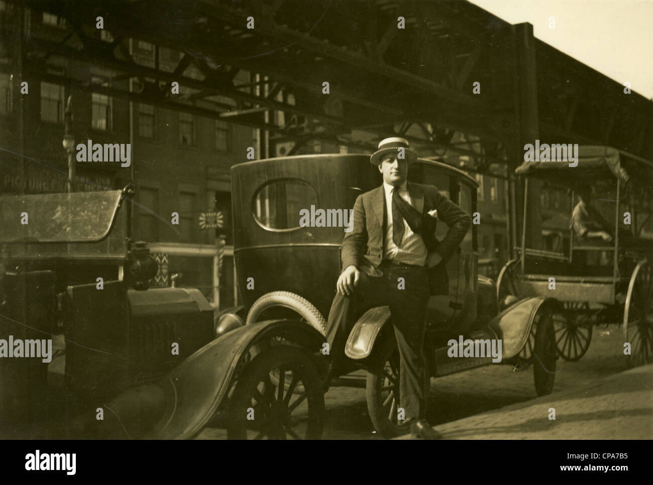 Circa 1920 photograph of a man with his car under the Washington Street Elevated segment of the Boston Elevated Railway. Stock Photo