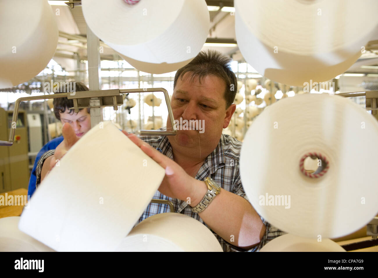 Spools of thread are being hung on the knitting machine, Burladingen, Germany Stock Photo