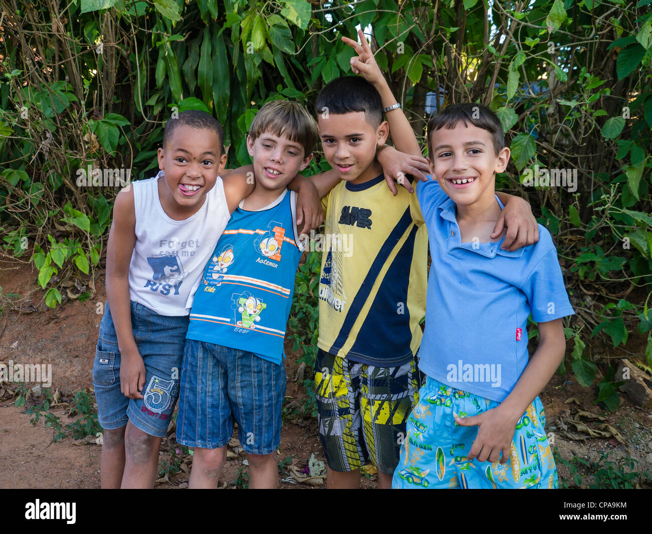Four 10-12 year old Cuban boys play around smiling, laughing and gesturing while standing together in Viñales, Cuba. Stock Photo