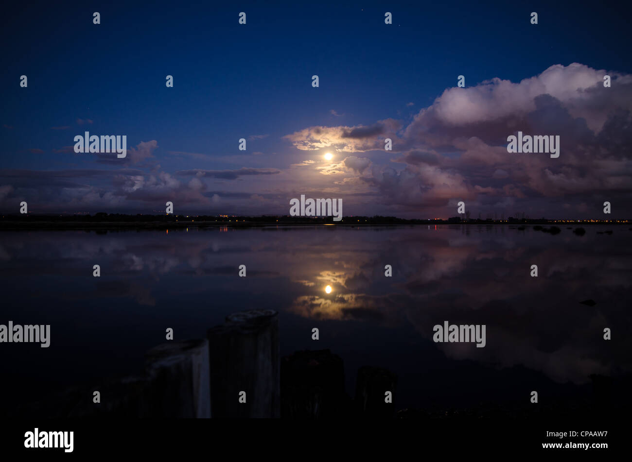 Moon rising and reflecting in the still water of a lake Stock Photo - Alamy