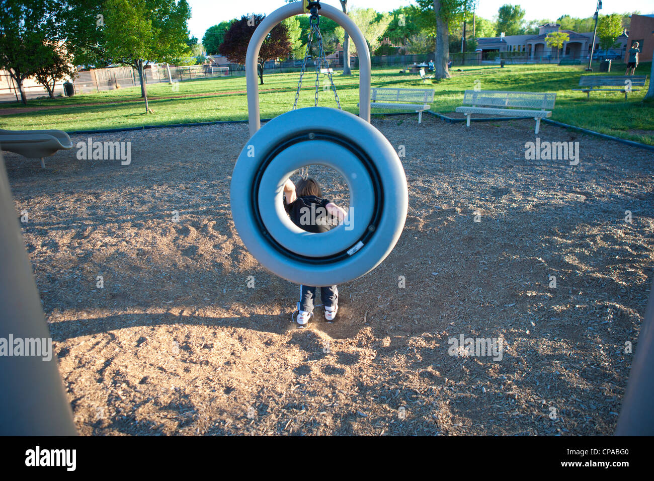 boy jumping out of a circular swing at a park Stock Photo