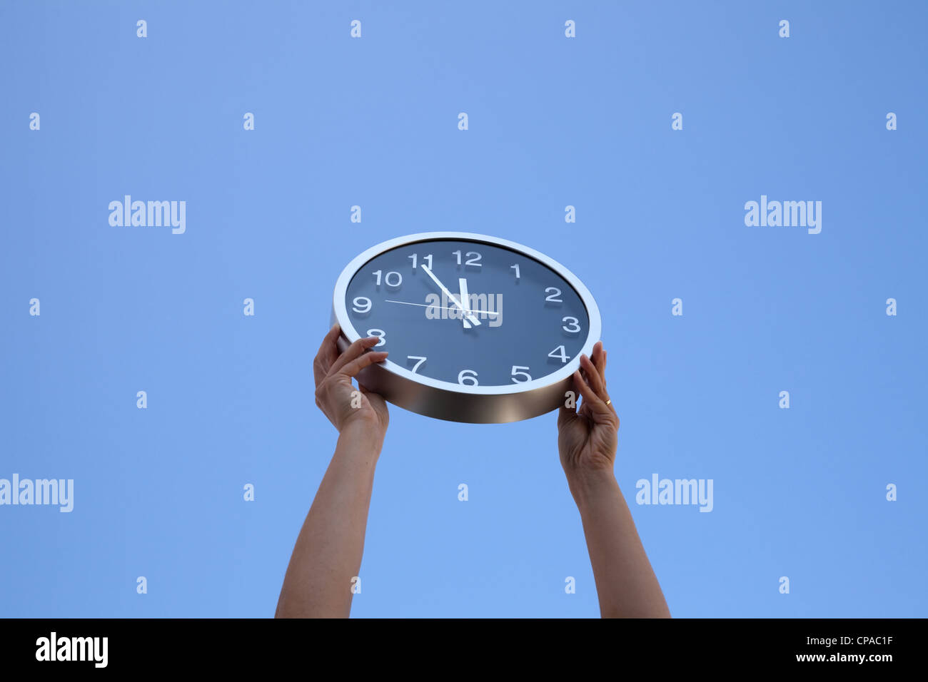 hands holding a wall clock up to the sky Stock Photo Alamy