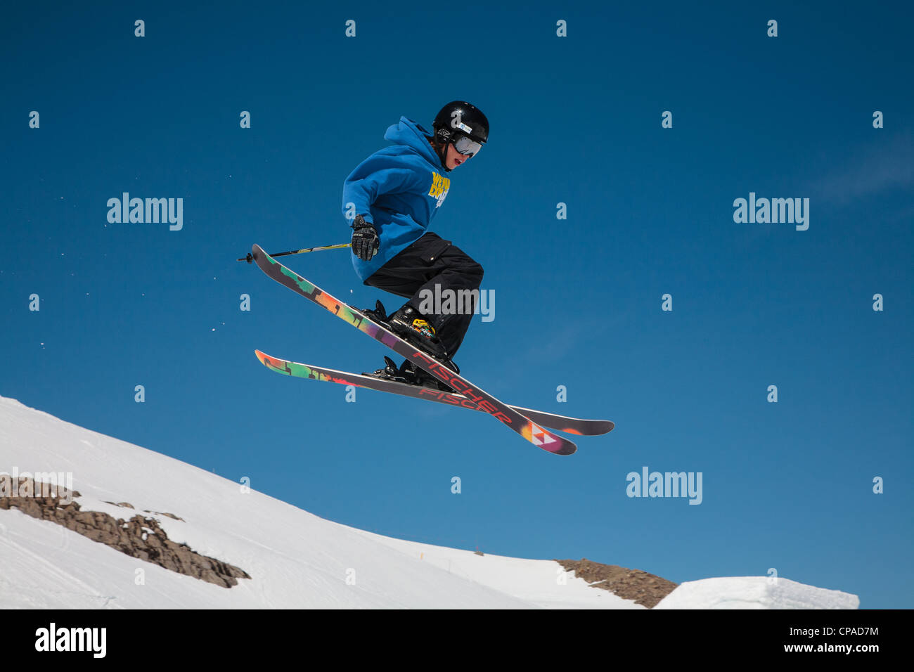 A free-style skier executes a jump against a clear blue sky. 1 of 2. Stock Photo