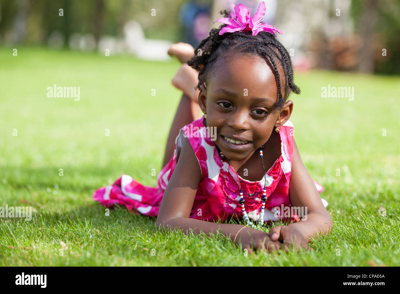 Outdoor portrait of a cute little African american girl lying down on the grass Stock Photo