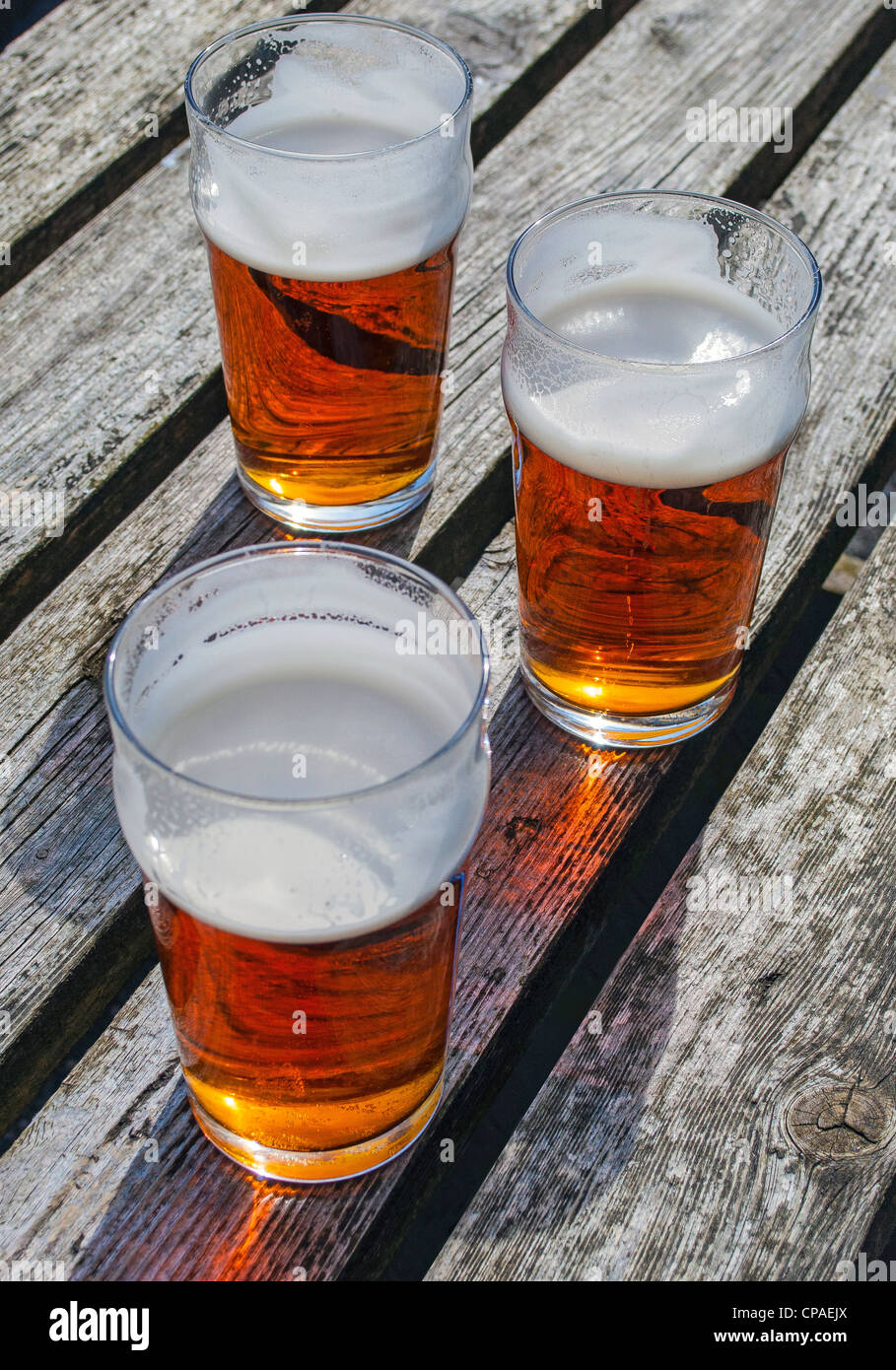 Three pints of ale on wooden table Stock Photo