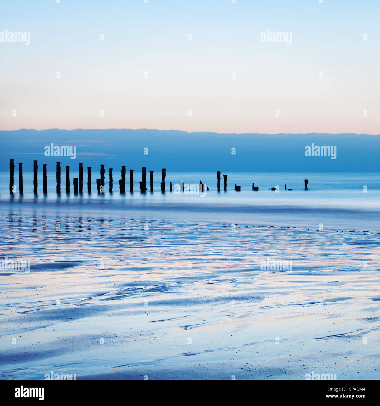 Old sea defences at dawn, smooth water from long exposure. Stock Photo