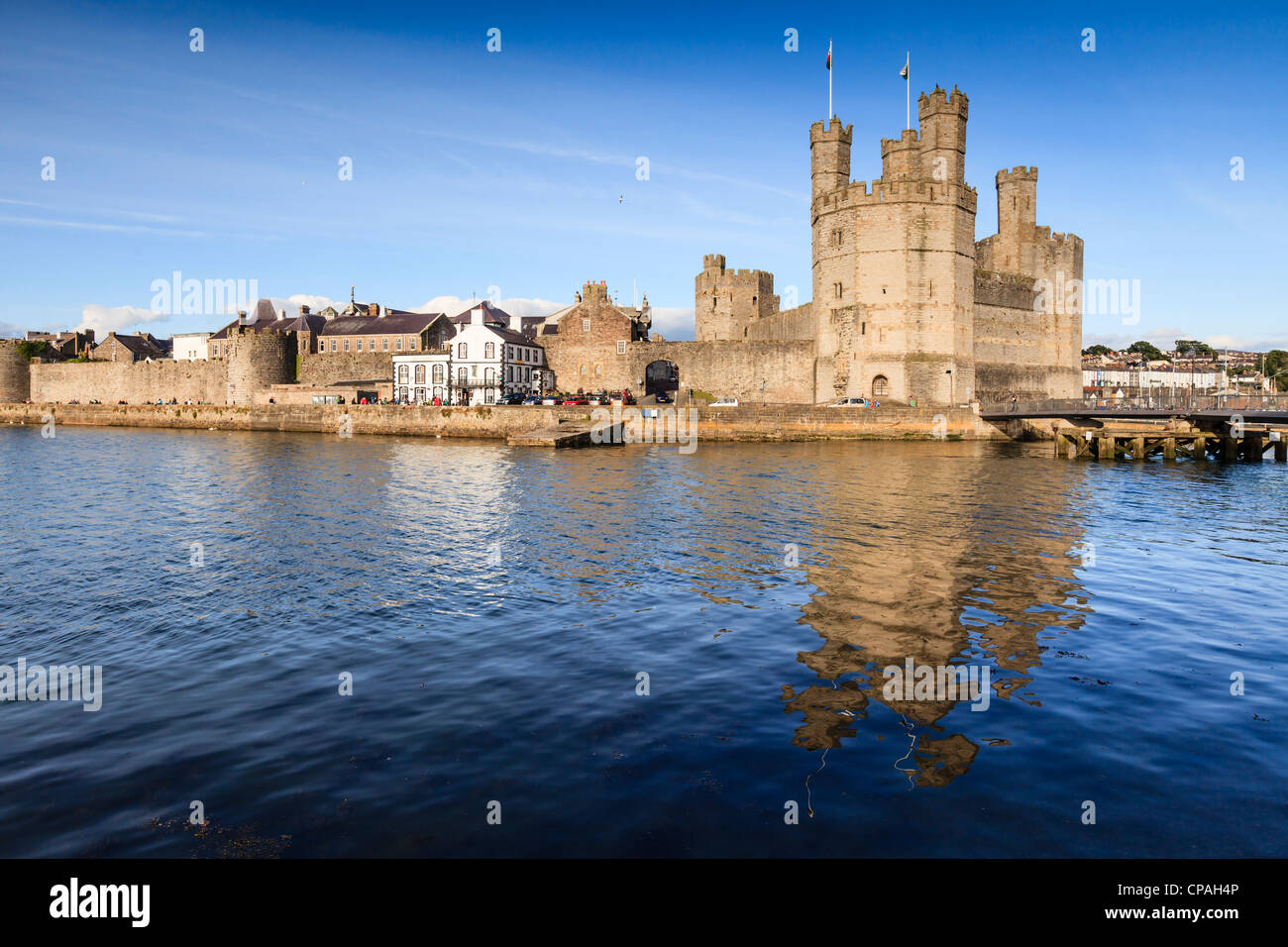 A bright summer evening at Caernarfon Castle, Gwynedd, North Wales. The castle is reflected in the River Stock Photo