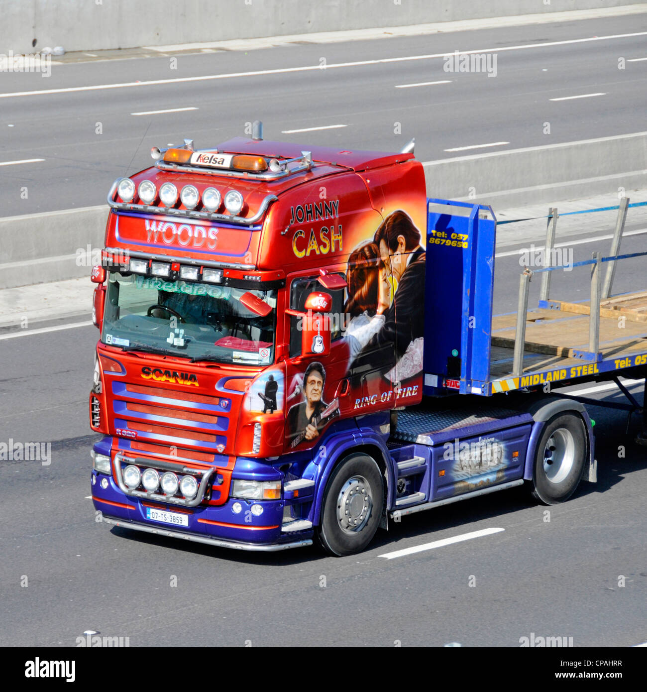 Johnny Cash lorry truck art graphics side front view of Scania semi cab tractor unit & flat bed trailer driving along UK motorway highway road England Stock Photo