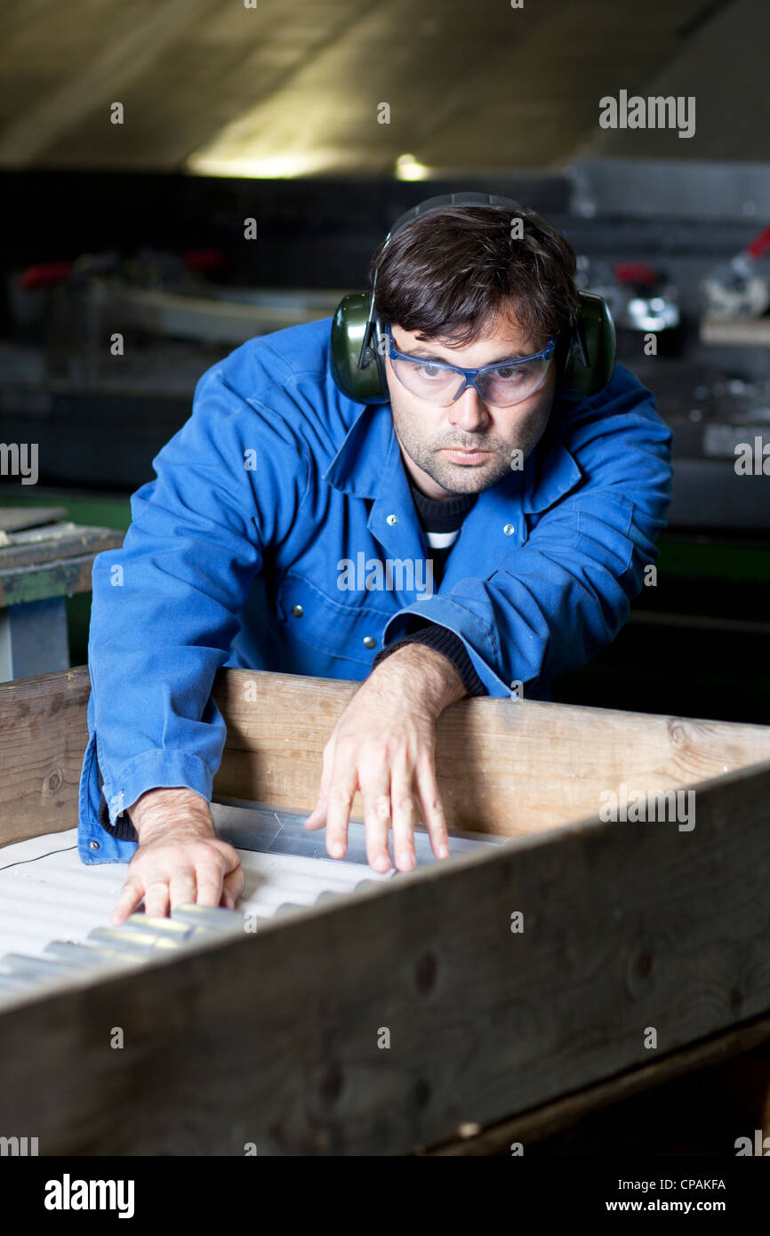Blue collar worker at machine in factory Stock Photo