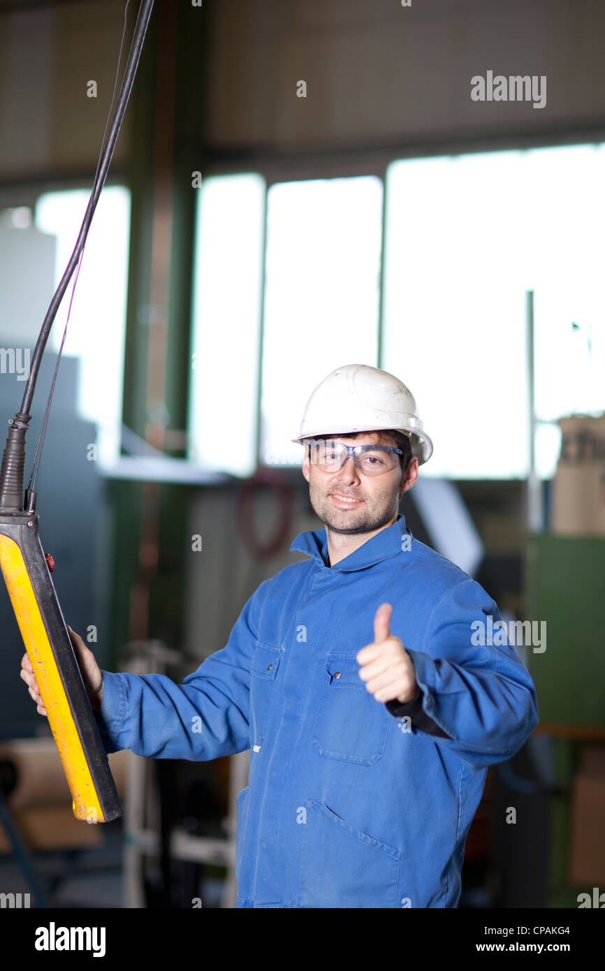 Blue collar worker using a crane in factory Stock Photo