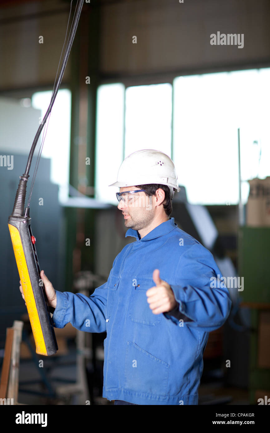 Blue collar worker using a crane in factory Stock Photo