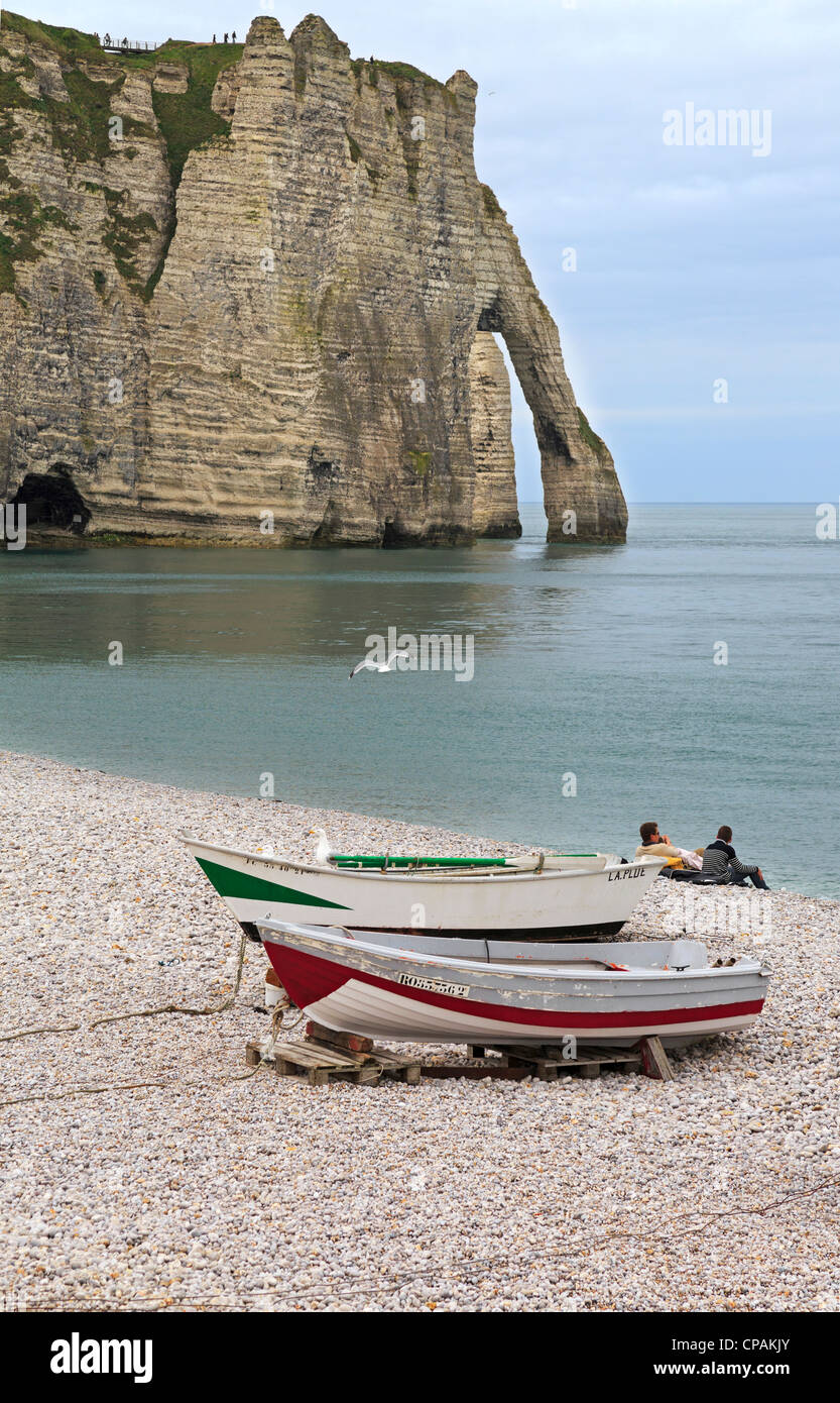Etretat beach and cliffs. Fishing dinghies drawn up on the pebble beach ...
