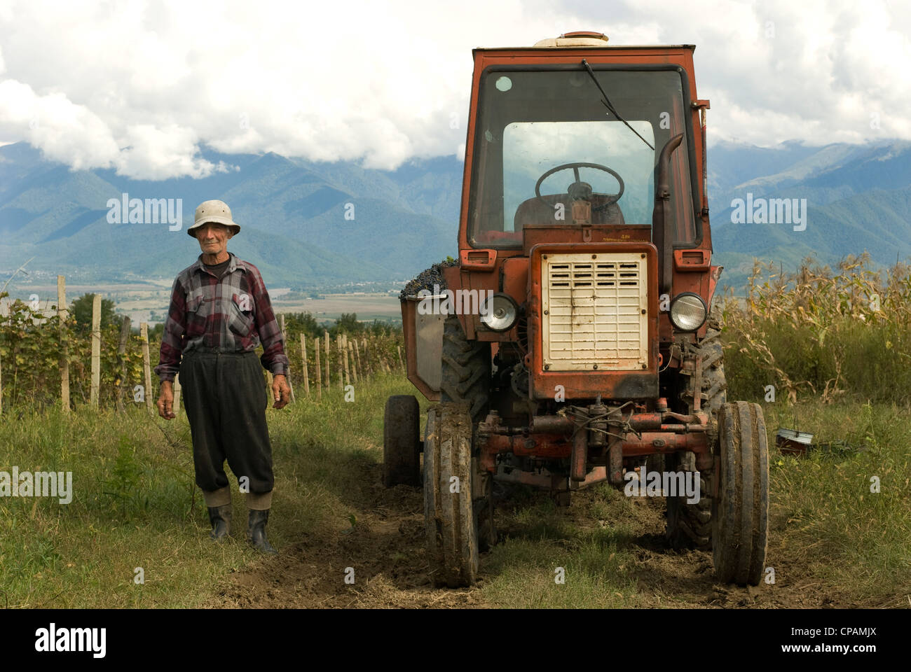 Tractor driver stands by tractor in Georgia, former Soviet Republic Stock Photo