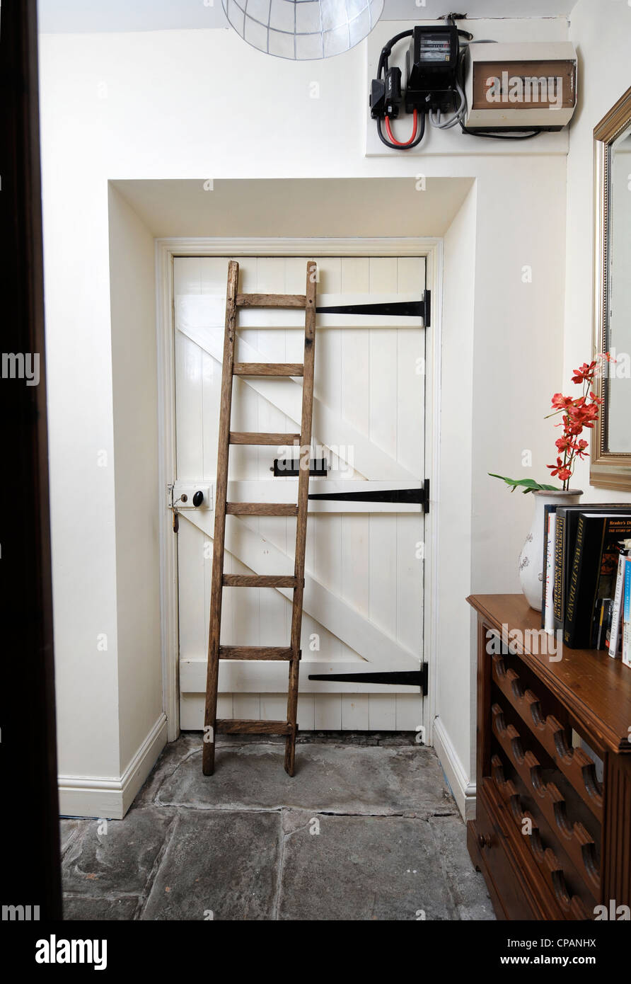A short wooden ladder stored in a corridor to allow inspection of a home's fuse box and electricity meter UK Stock Photo