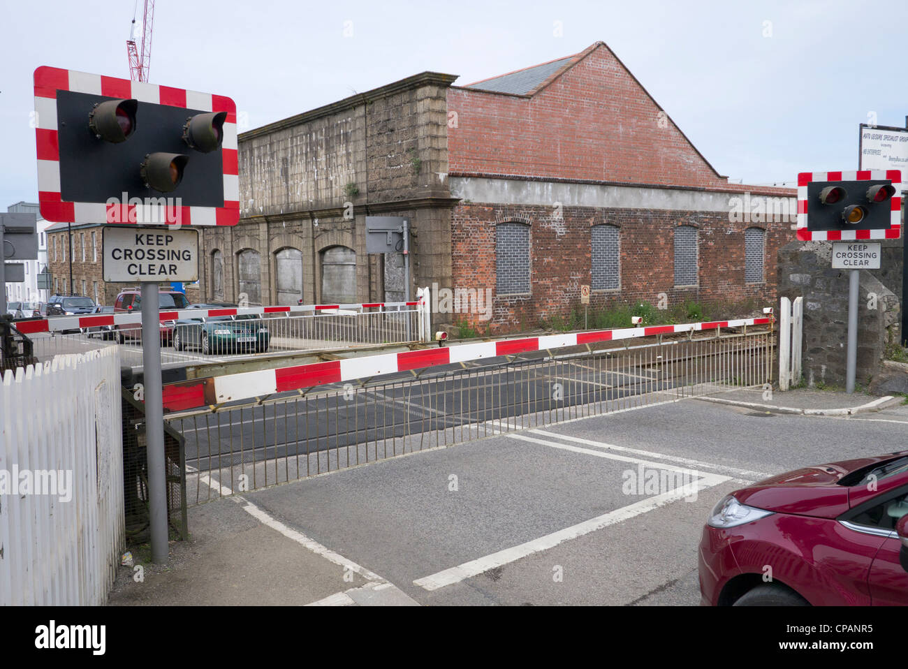 British railway level crossing barrier gate closed before a train passes through in Camborne, UK. Stock Photo