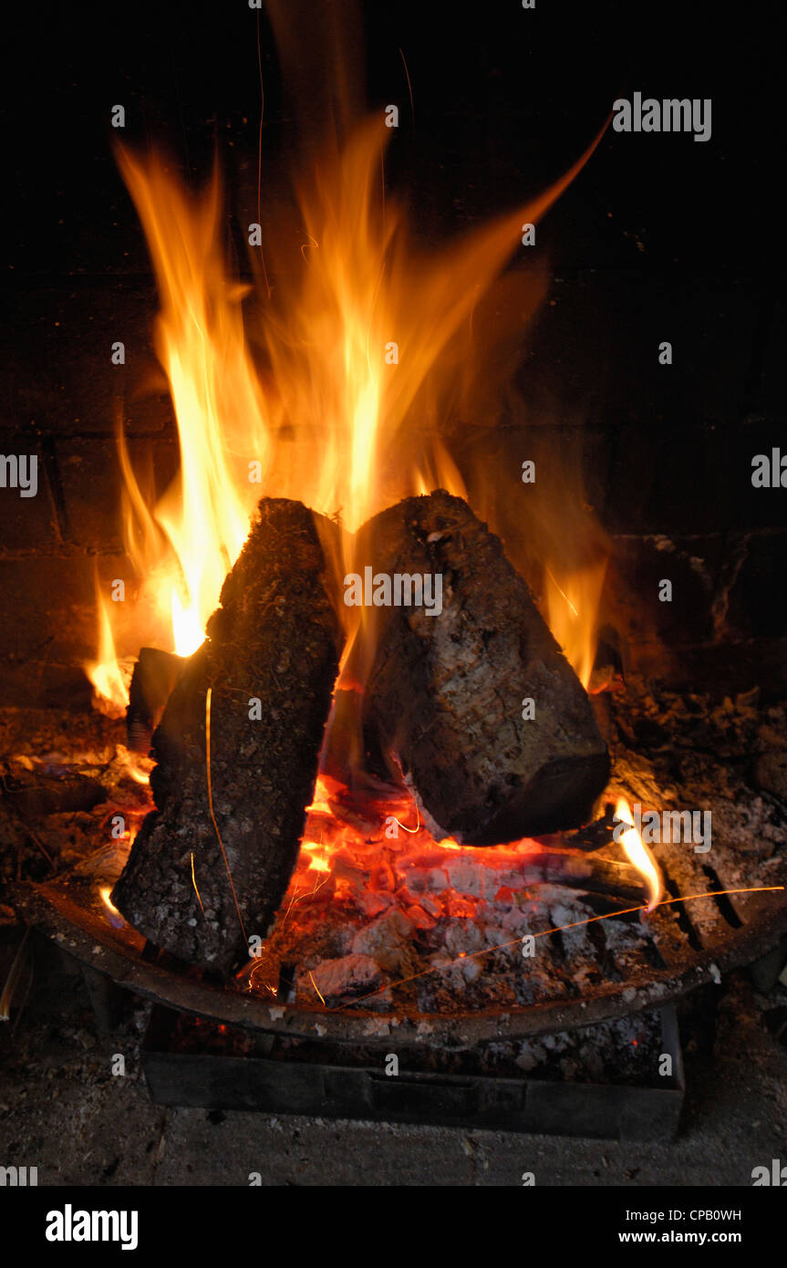 Open fire with logs burning in a simple hearth with bright flames
