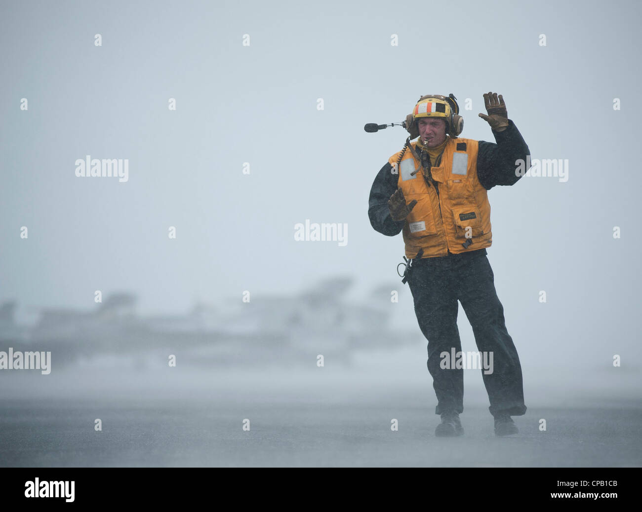 Aviation Boatswain's Mate (Handling) 2nd Class Jathan Lane directs the movement of aircraft during foul weather on the flight deck aboard the Nimitz-class aircraft carrier USS Carl Vinson (CVN 70). Carl Vinson and Carrier Air Wing (CVW) 17 are deployed to the U.S. 7th Fleet area of operations. Stock Photo