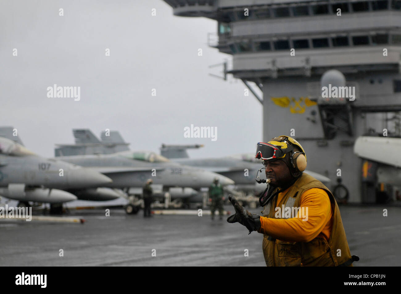Aviation BoatswainÕs Mate (Handling) 2nd Class Dwayne Foster directs aircraft on the flight deck during foul weather aboard the Nimitz-class aircraft carrier USS Carl Vinson (CVN 70). Carl Vinson and Carrier Air Wing (CVW) 17 are deployed to the U.S. 7th Fleet area of operations. Stock Photo
