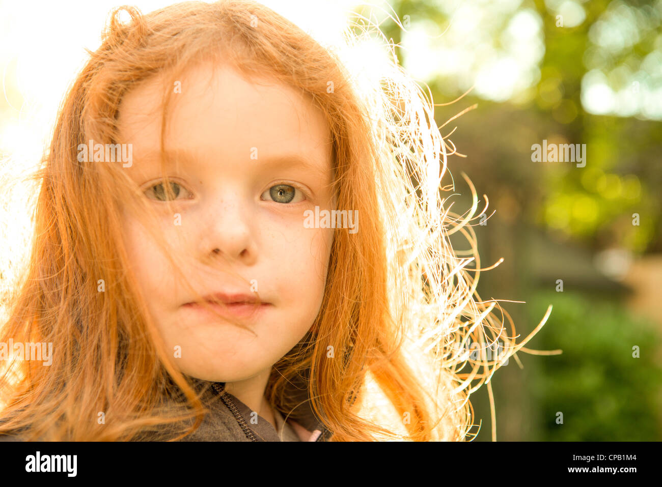 Little girl with ginger hair looking to camera in her summer garden Stock Photo