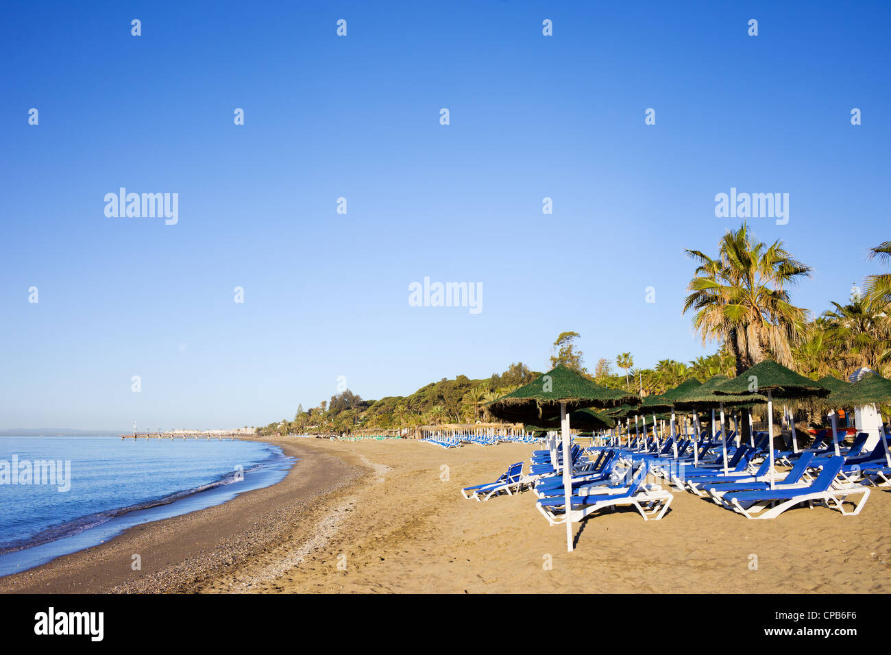 Sun loungers on a sandy beach by the Mediterranean Sea at the popular resort of Marbella in Spain. Stock Photo